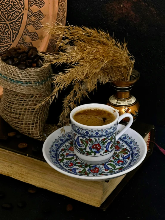 an artistic cup is displayed on a table with a vase and bag