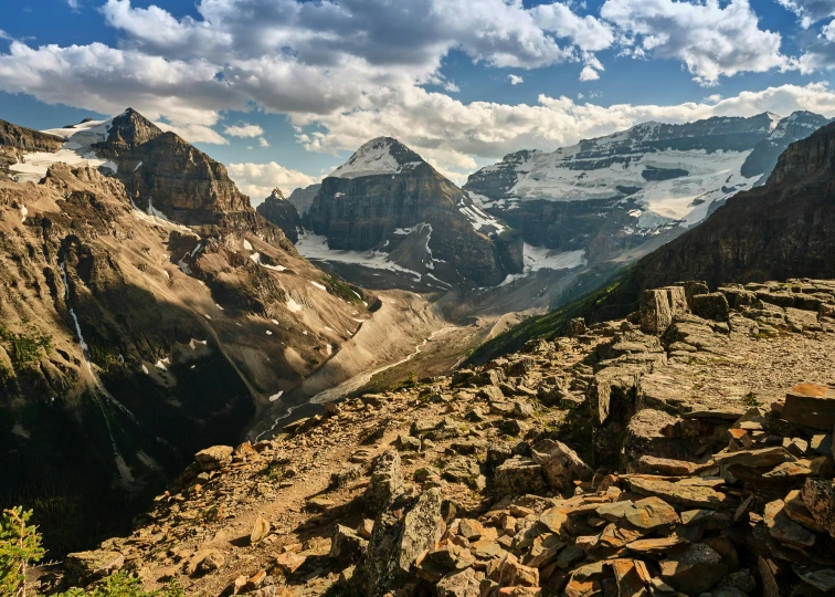 a rocky mountain with some snow capped mountains behind it