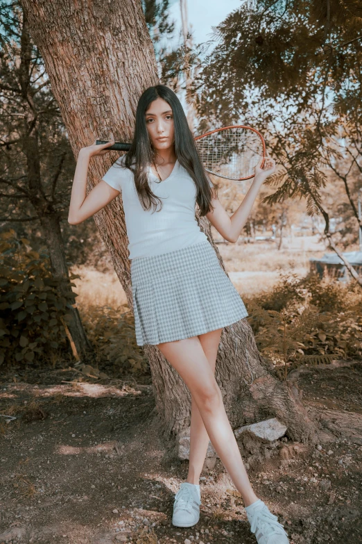 a woman poses with a basketball in front of a tree