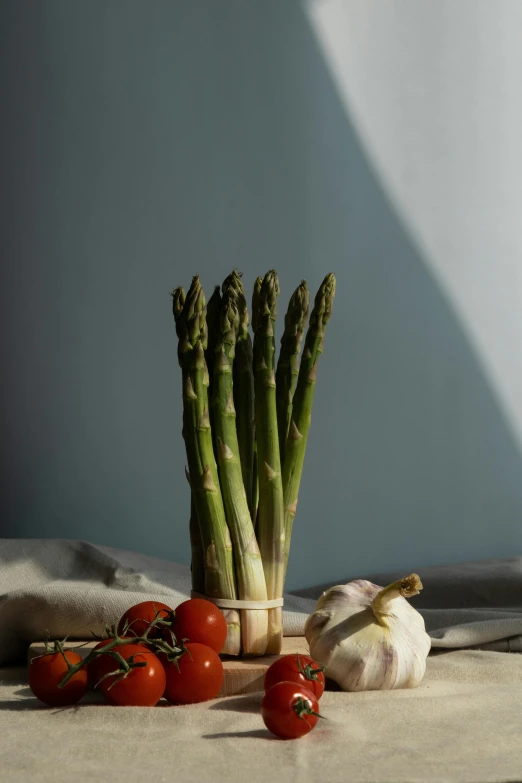 asparagus and tomatoes sitting on the floor next to a cloth