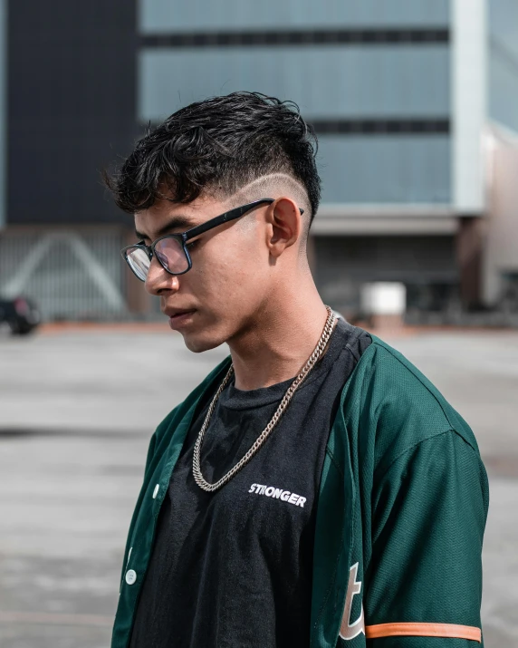 young asian man in black glasses stands outside