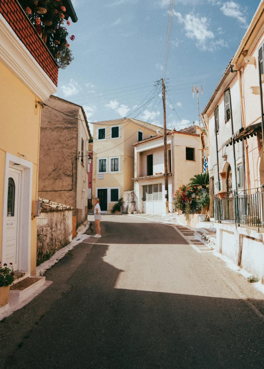 a narrow city street is surrounded by yellow and white buildings