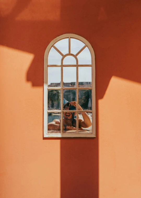 the reflection of a person taking a po through an open window