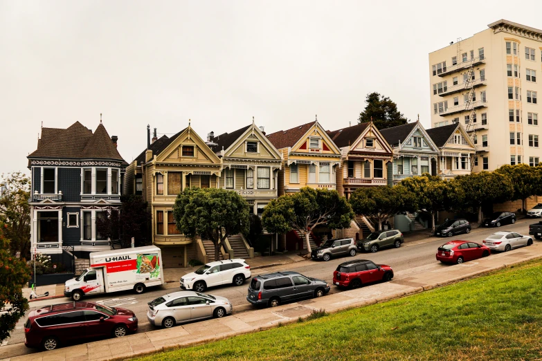 several cars parked on the side of a road lined with houses