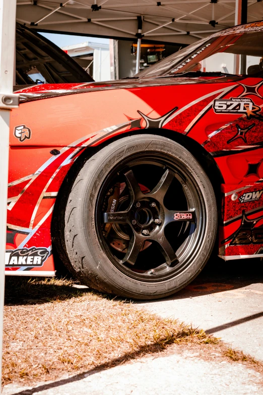 a red car with black rims and a blue tire cover