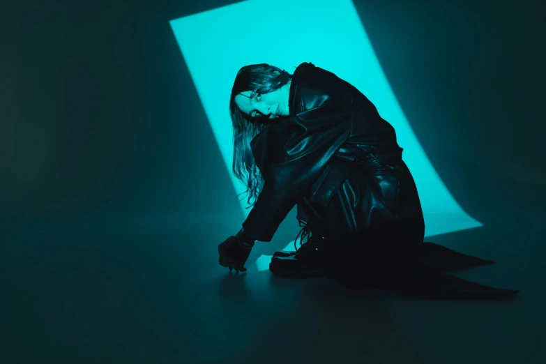 woman in leather jacket sitting against wall