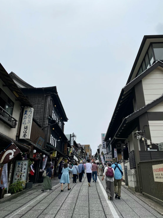 people are walking through a town that is busy with shops