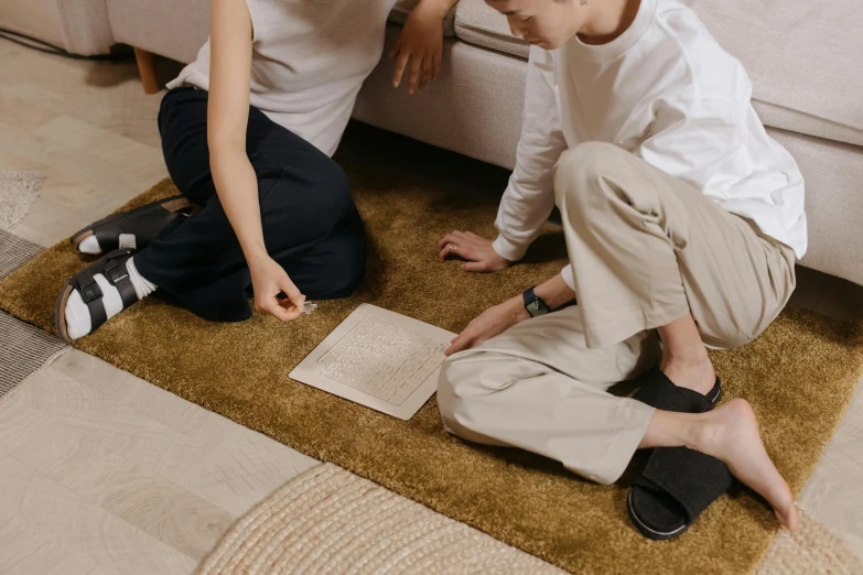 two children sitting on the floor while looking at soing