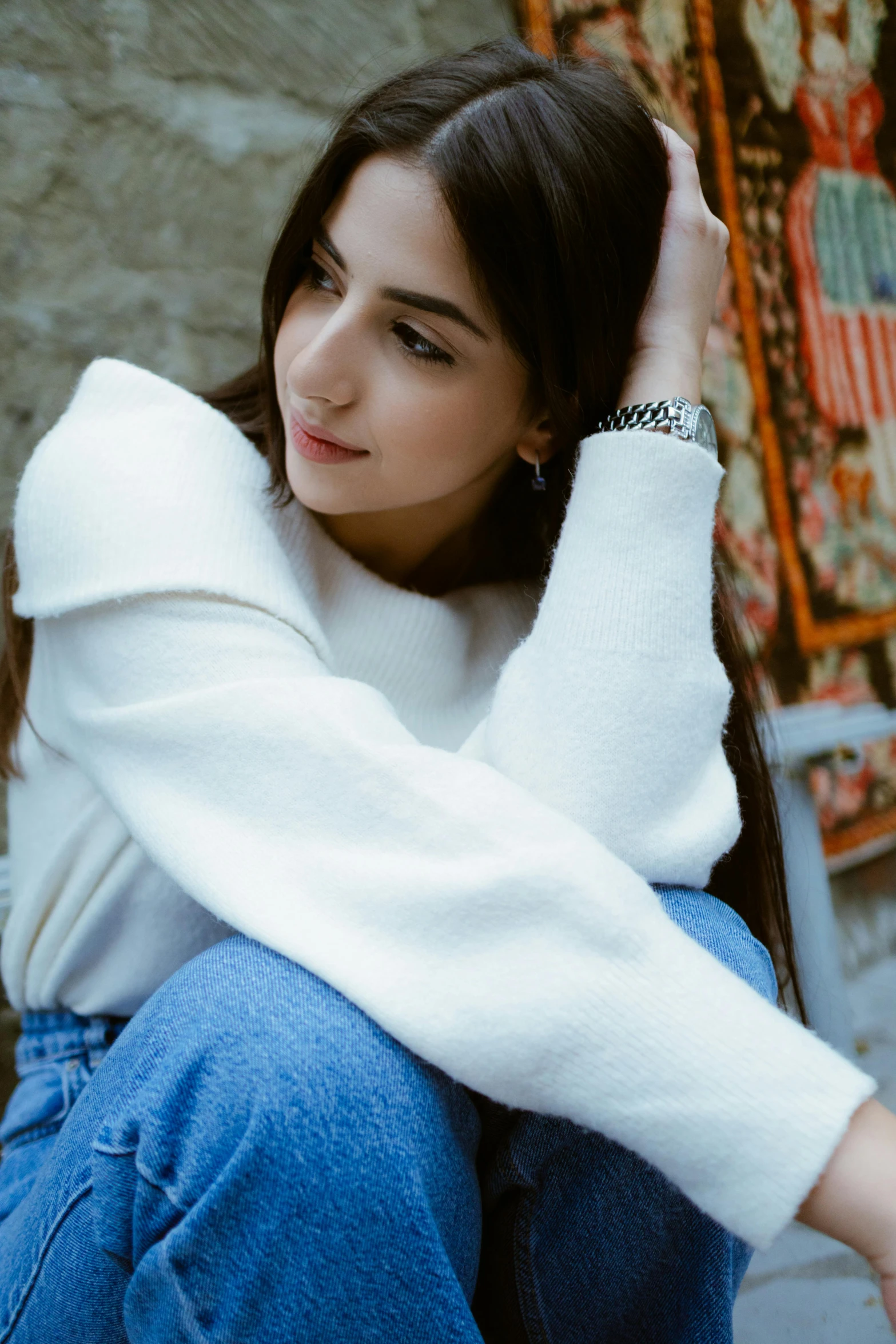 a woman is sitting down holding her hands behind her head