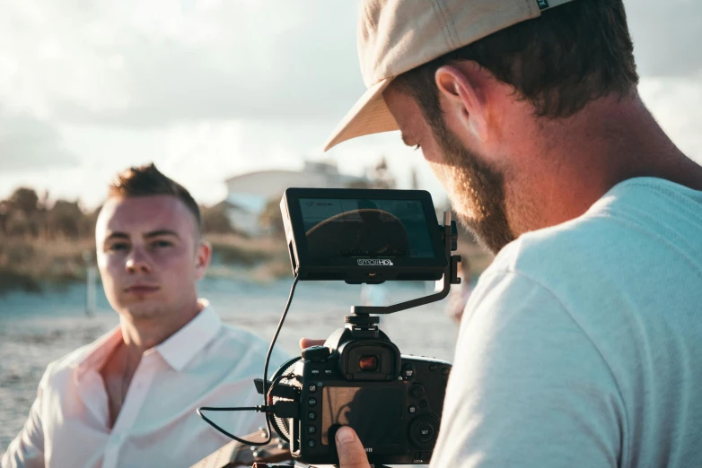 a man with a hat and camera near the water