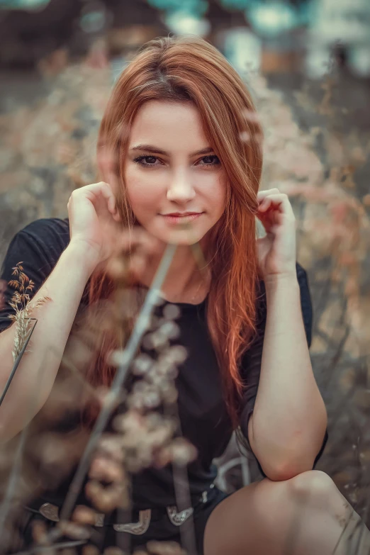 a girl is sitting in the grass with her head tilted