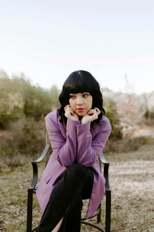 a woman with her hand on the face, sitting in an old chair