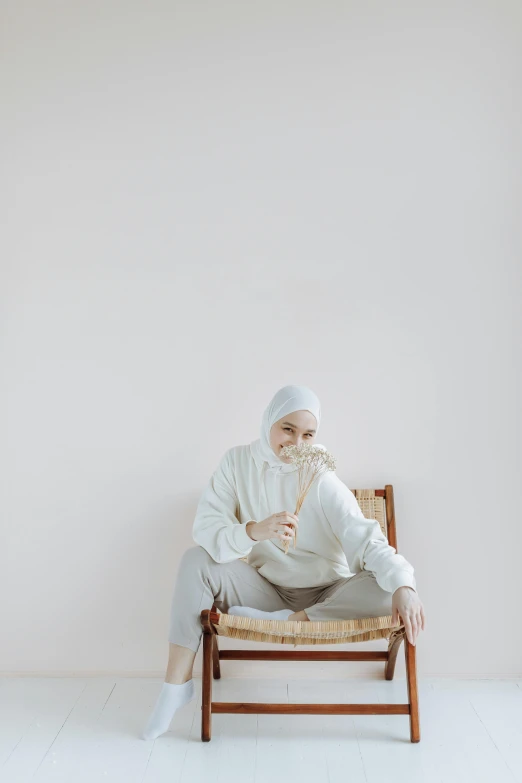 man in white clothing sitting on brown chair against wall