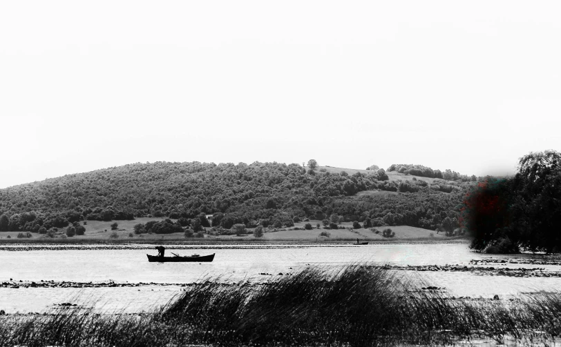 a lone boat sits on the water near the hills