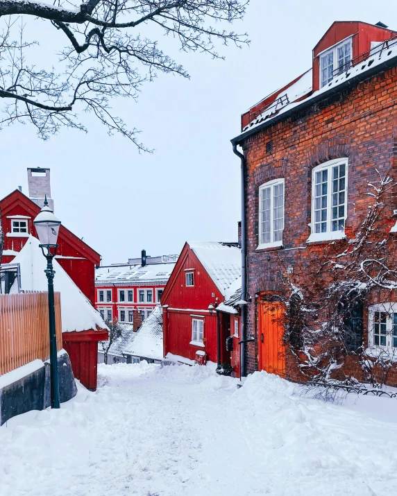 a city street covered in snow with a red brick house
