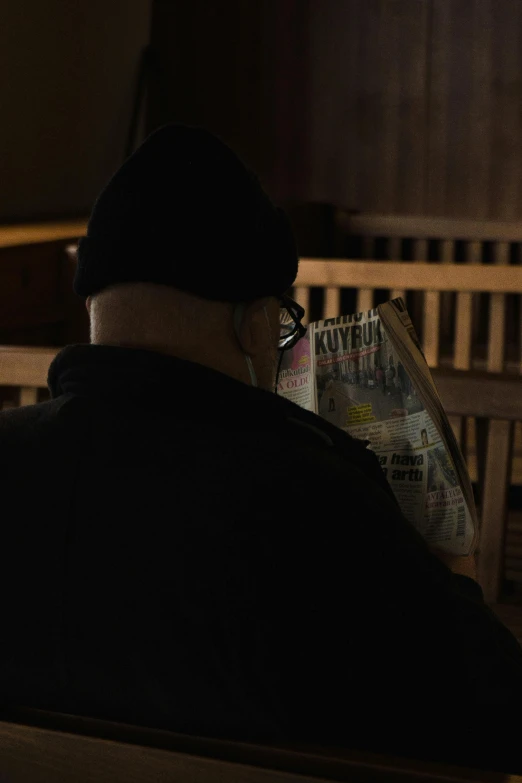 a man reading a news paper in the dark