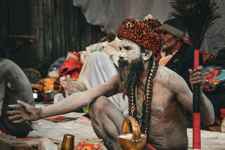 a man painted white and sitting on the ground in front of his face