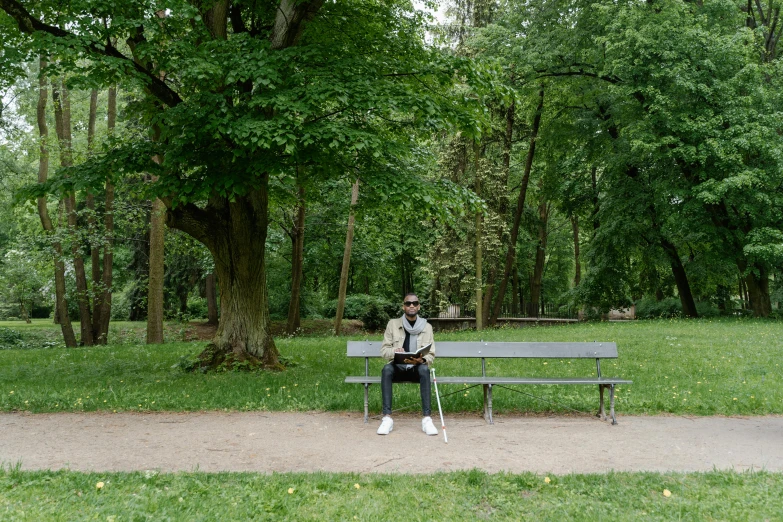 a man sitting on top of a bench in a park