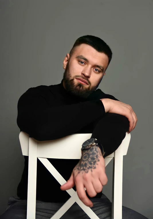 a man with a tattoo sitting on a white chair