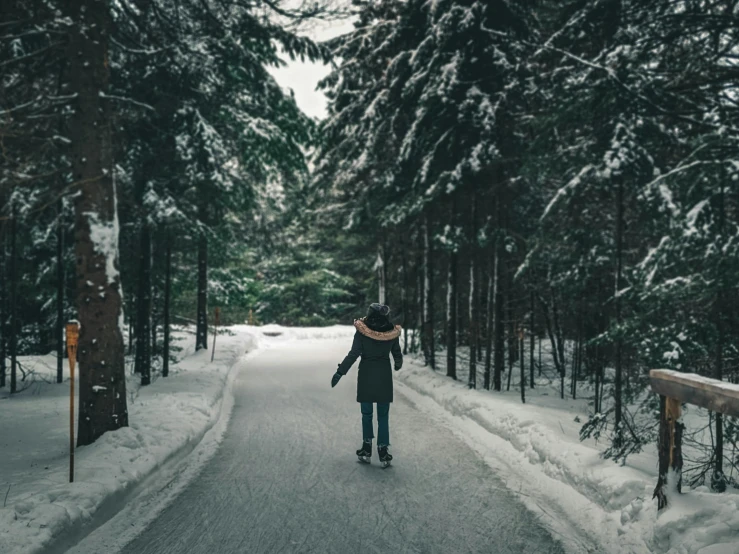 a person riding on top of a snow covered ground next to trees