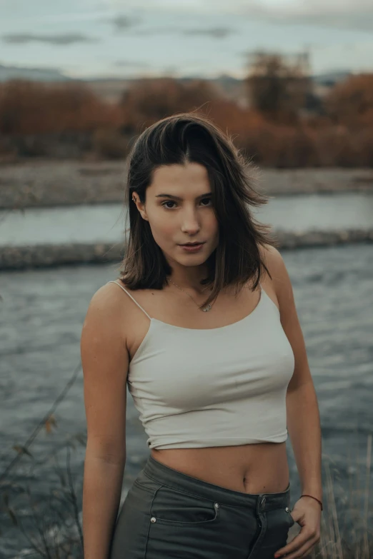 a pretty young woman posing in front of a river