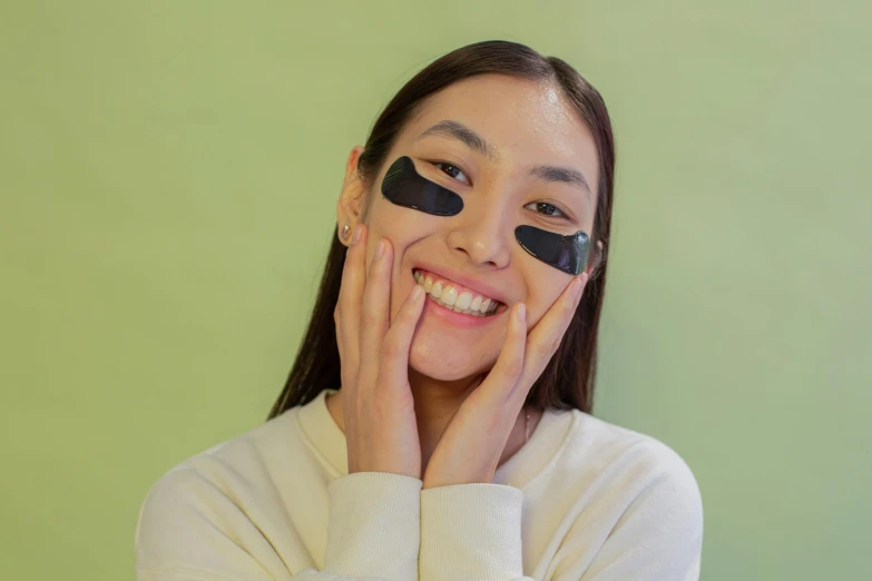 a woman smiles while wearing eye patches