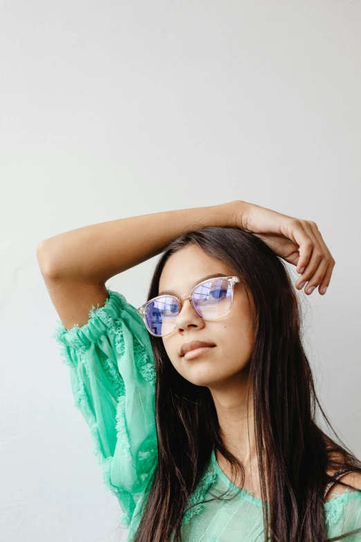 a beautiful young woman wearing sunglasses holding her hair