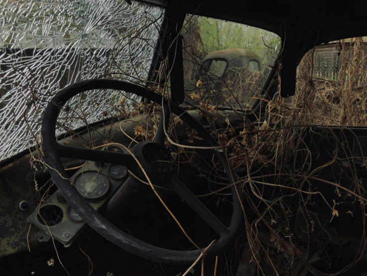 there is an old rusted out car in the field