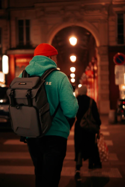 a person in a red hat walks across the street