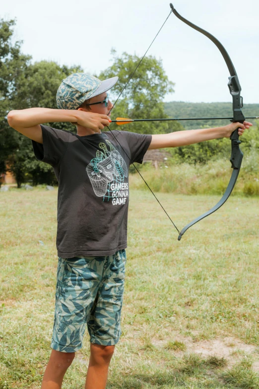 a man aims a bow while standing in a field