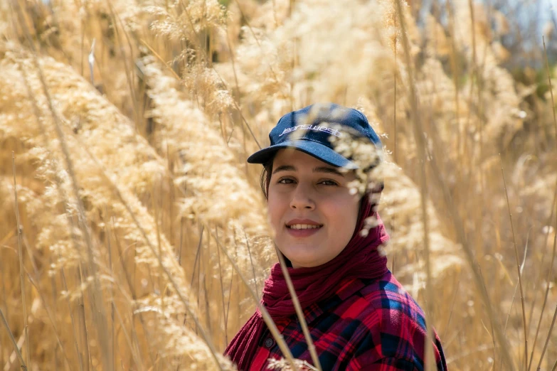 a  in a blue hat stands among tall brown grass