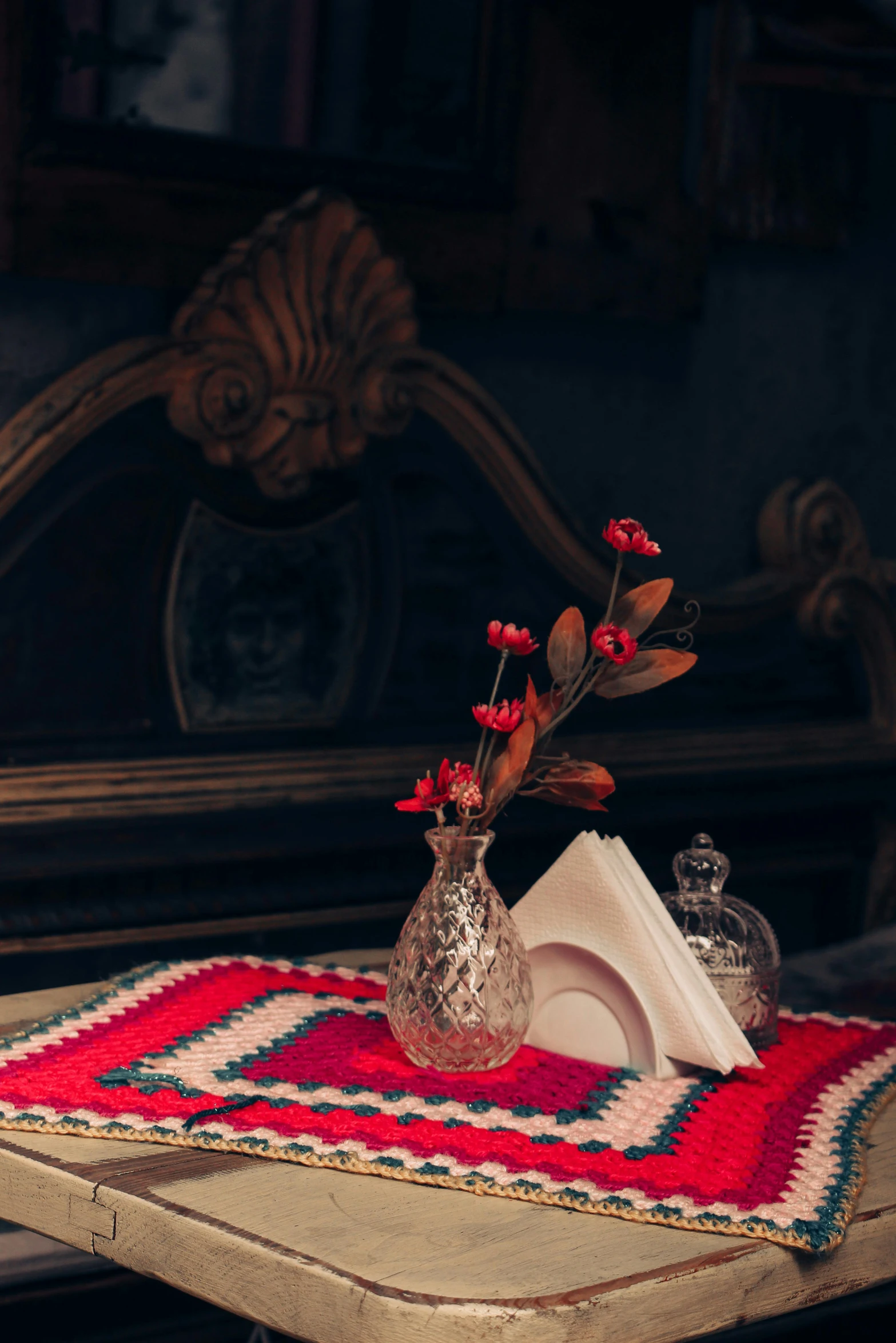 a small vase with red flowers is on a red and white table mat