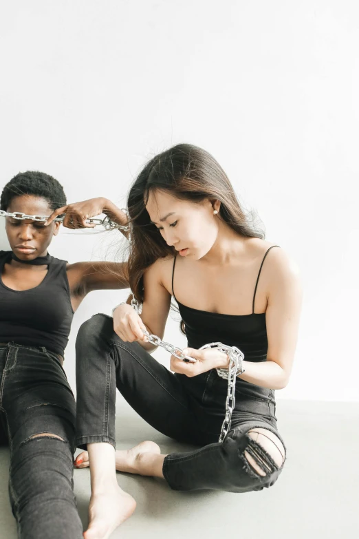 two women are sitting on the floor using cellphones