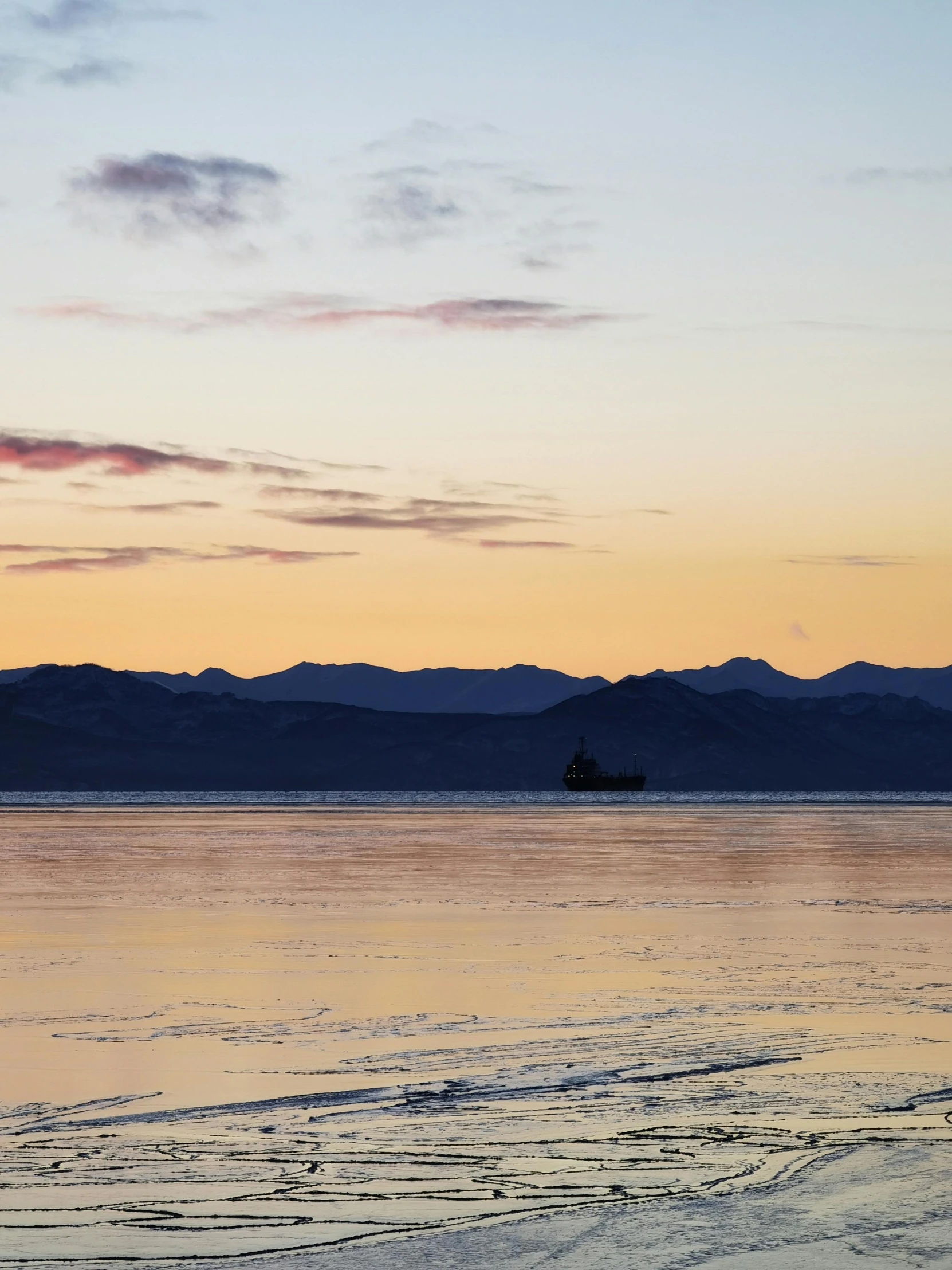 the sky at dawn with a boat out in the water