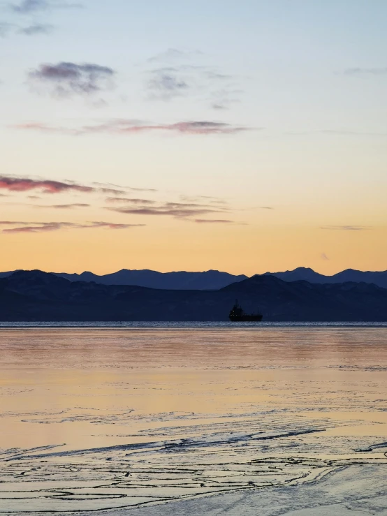 the sky at dawn with a boat out in the water