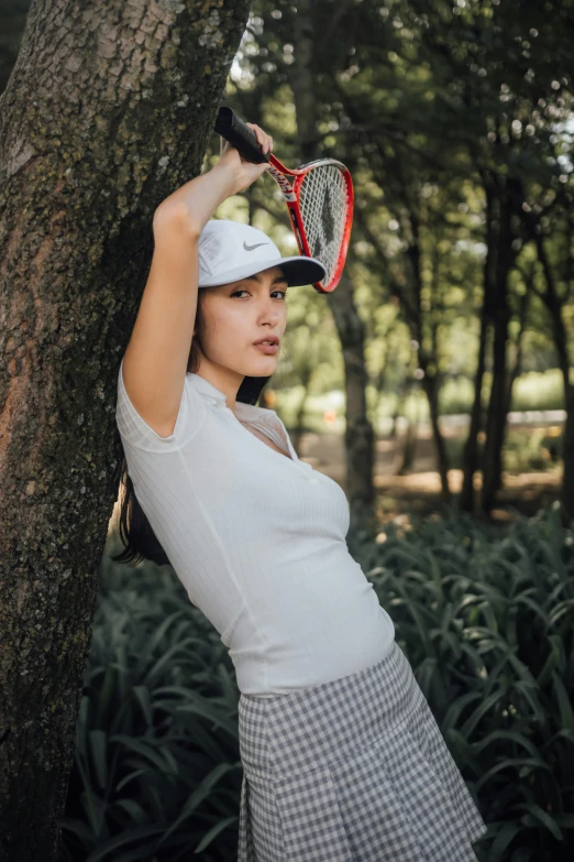 woman holding tennis racket on the side of tree