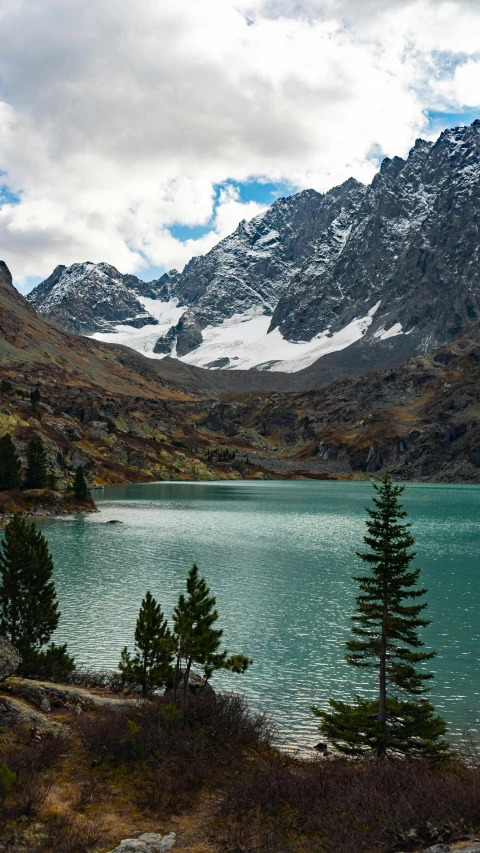 a couple of people sitting on the shore of a lake