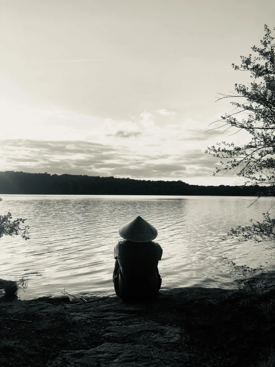 the person is sitting on a bench overlooking the water