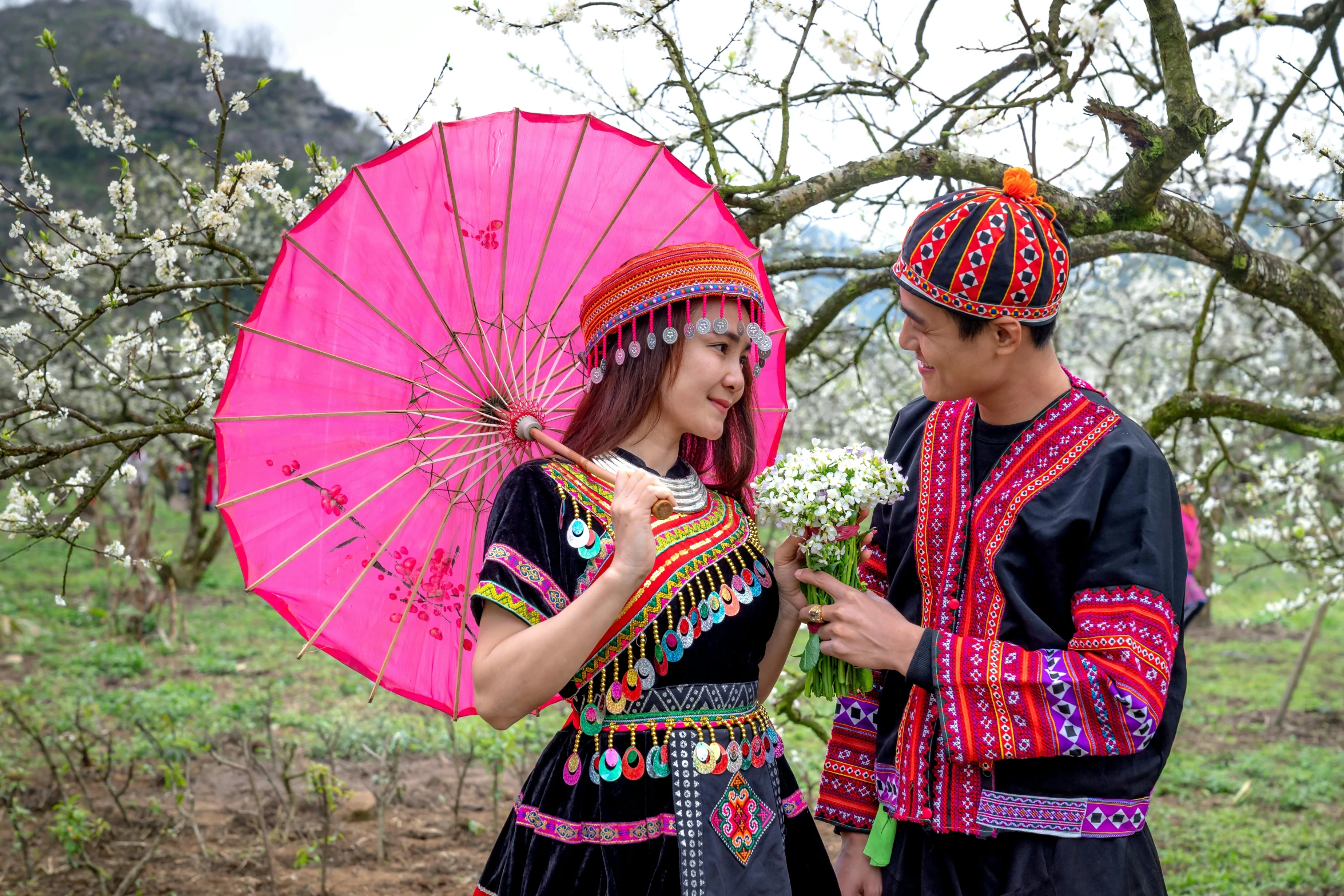 young couple dressed in costumes under cherry blossom trees