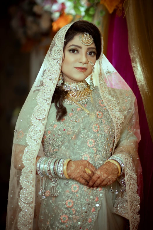 a bride wearing a white dress with gold jewelry