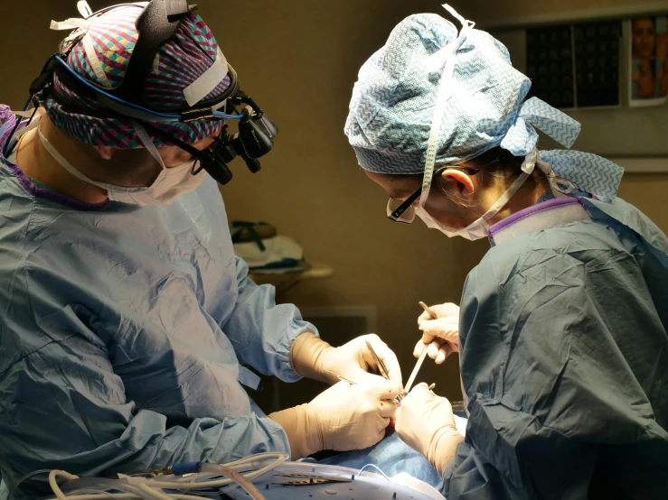 two surgical personnel performing  on the stomach of a patient