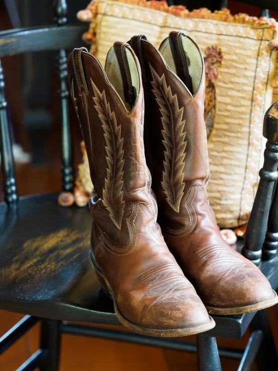a pair of brown cowboy boots on top of a chair