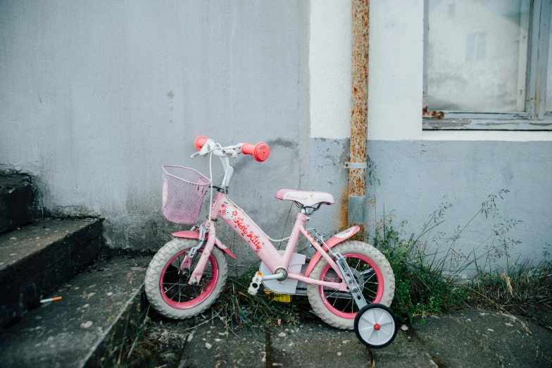 a pink bicycle sitting outside of a gray house