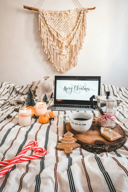 the laptop is open on the bed next to some candy and gingerbreads