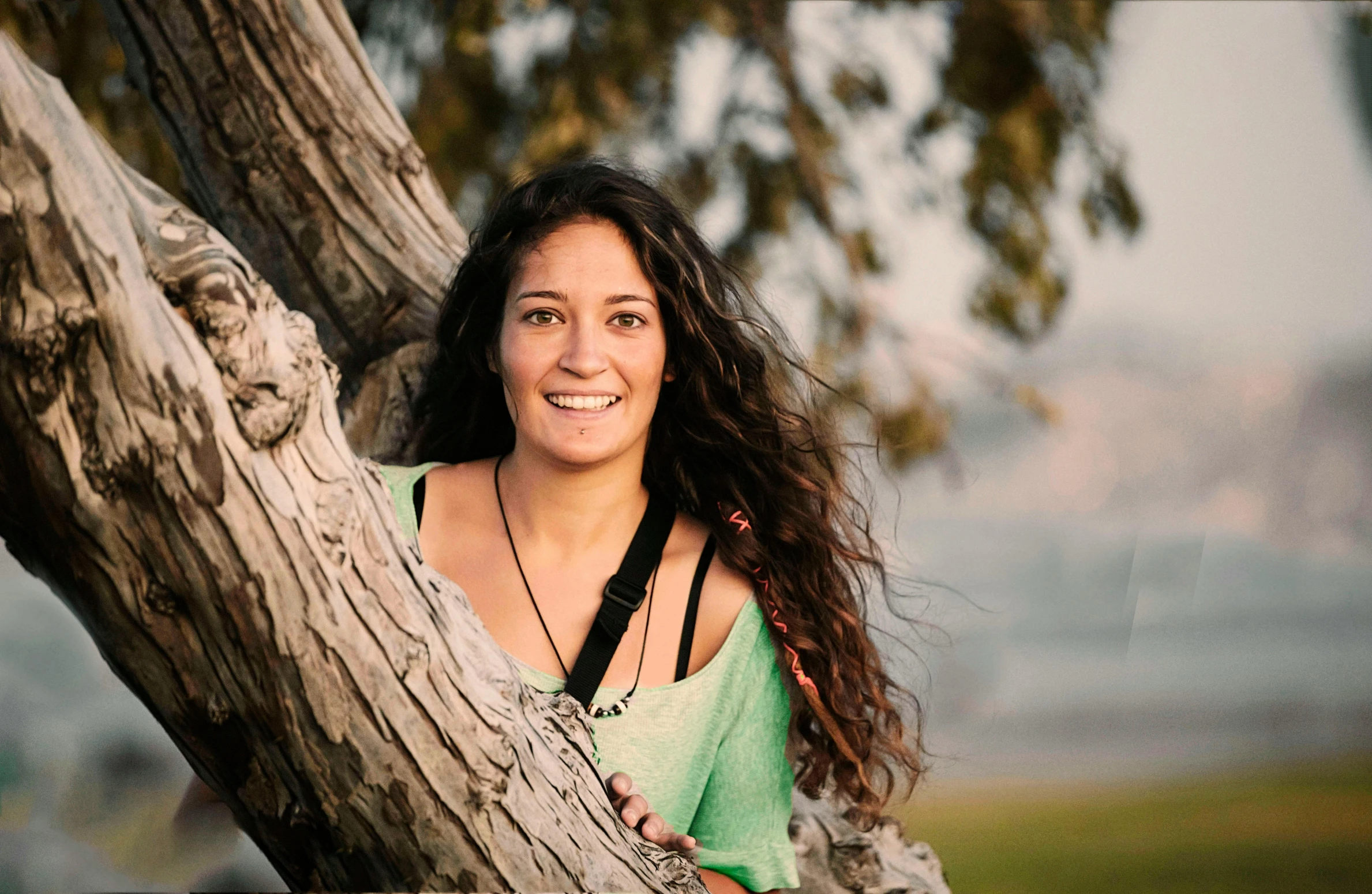 a woman leaning up against a tree, wearing headphones