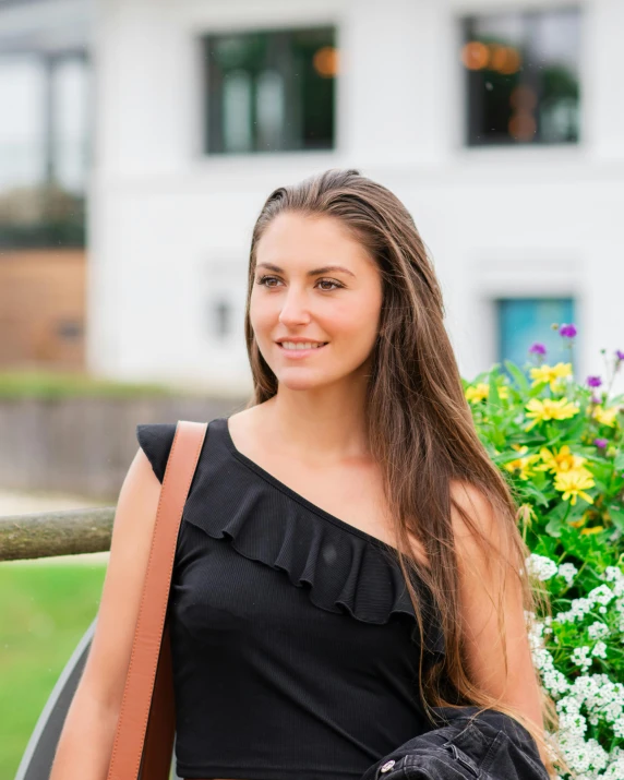 a woman is standing near a bush with flowers