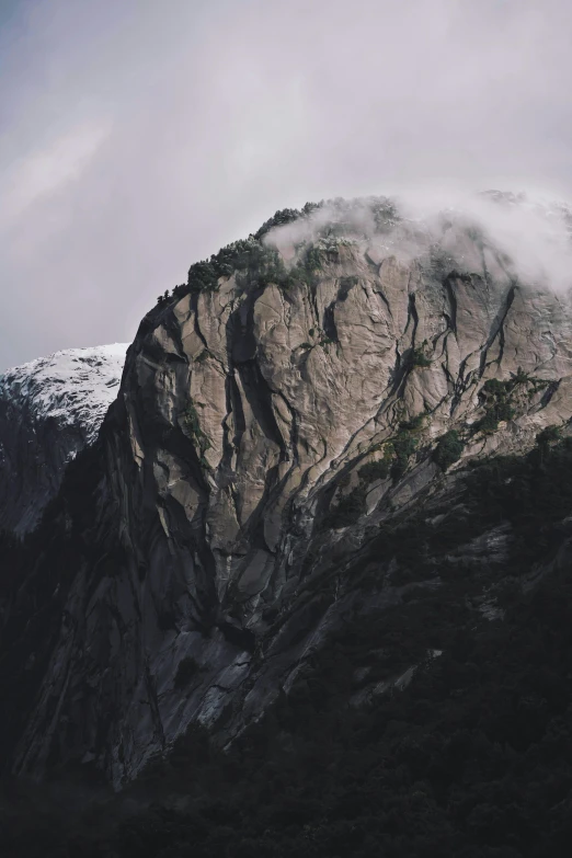 there is a large rock on a hill with a few clouds