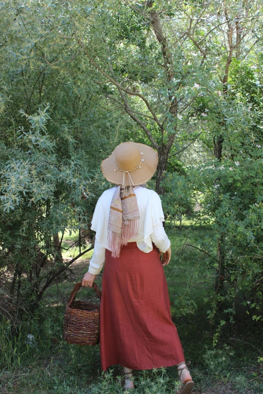 a woman in a hat standing on grass in the forest