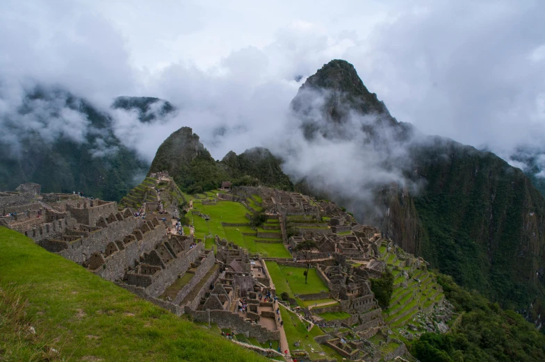 a mountain scene with a grassy area and ruins