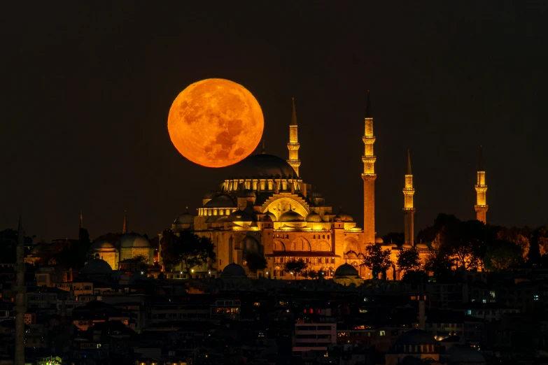a full moon rises over a cathedral as a silhouette of the city in the background